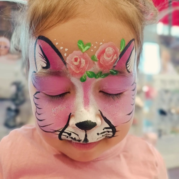 Enfant souriant avec un maquillage coloré et féerique lors d'un événement festif